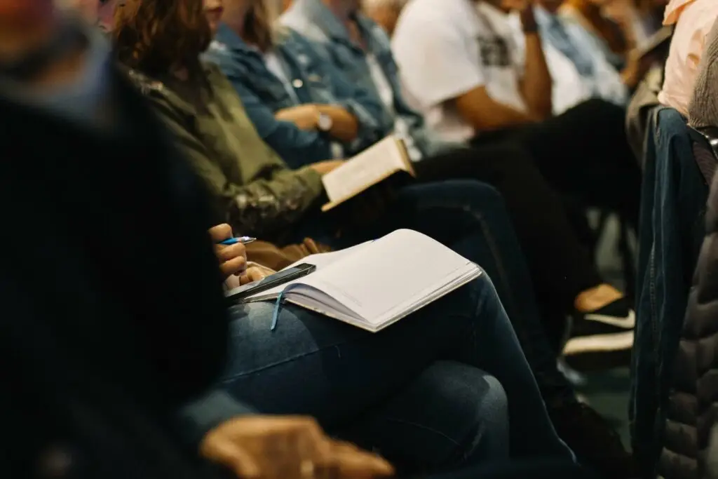 An image of people sitting at a lecture taking notes representing Dare 2 Share's blog titled 6 Essentials for Youth Leader Training.
