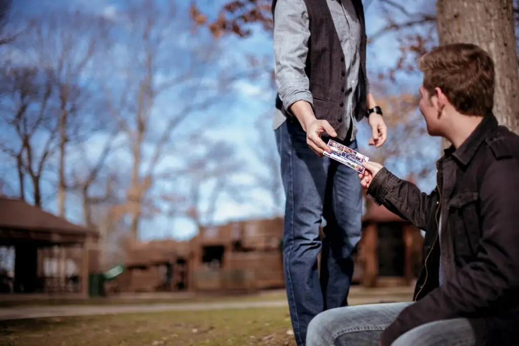 two teenagers outside and one is handing the other a gospel tract representing how you can prioritize evangelism.