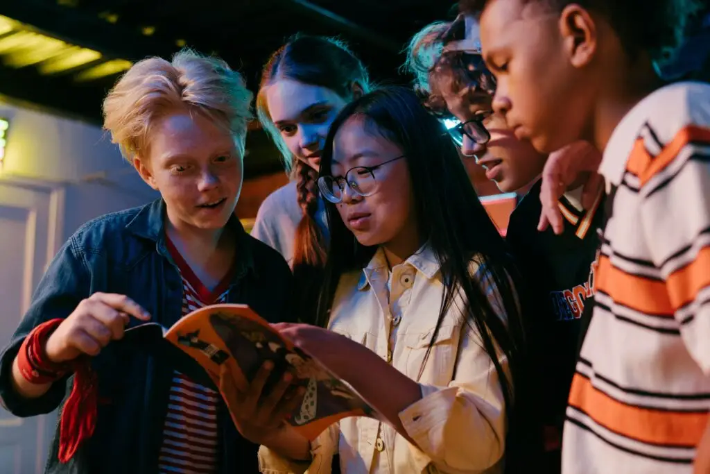 A group of teenagers looking at the instructions for a youth ministry game together.