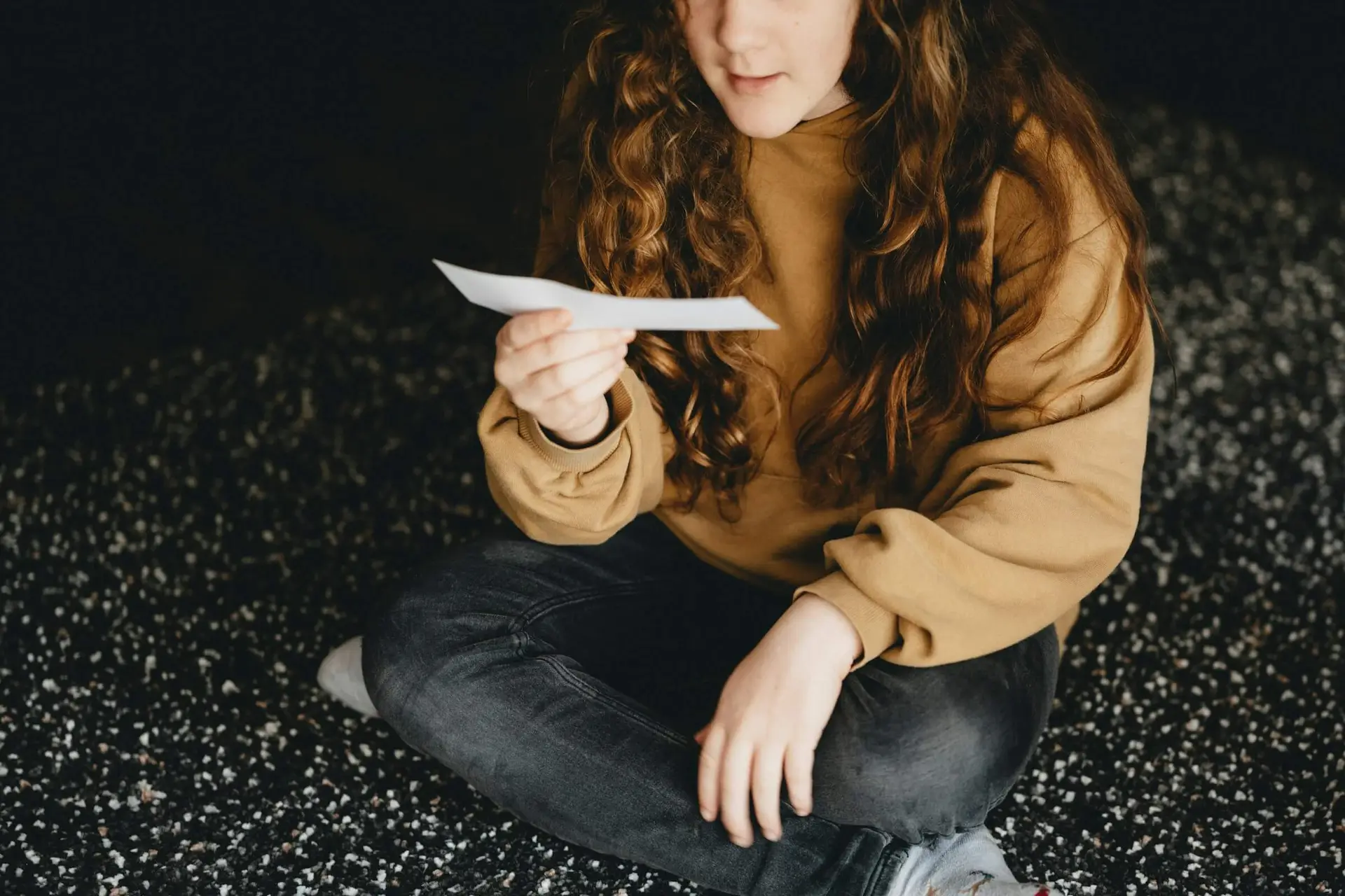 A teenager reading a piece of paper representing Dare 2 Share's blog titled Indoor Youth Group Games With Spiritual Applications [5 Games]