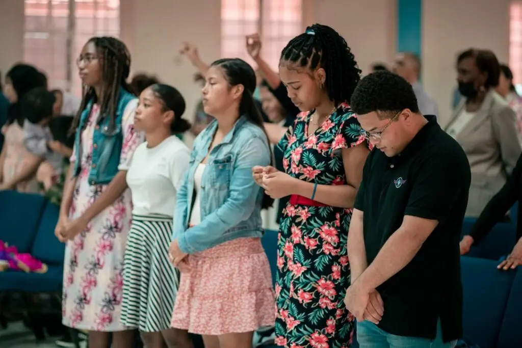 An image of teenagers praying at church representing Dare 2 Share's blog titled The Power of a Strong Prayer Life on Youth Ministry which encourages youth leaders to pray for teens.