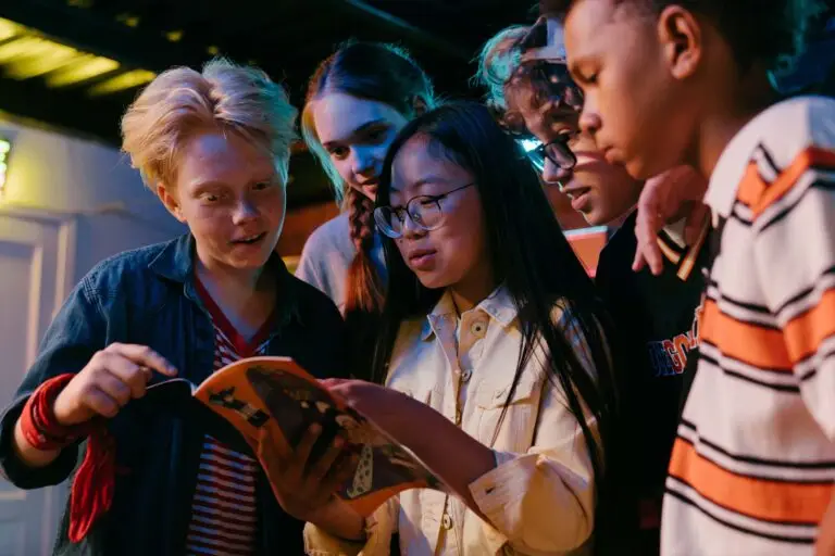 An image of students looking at a book representing Dare 2 Share's blog titled Youth Group Games With a Purpose.