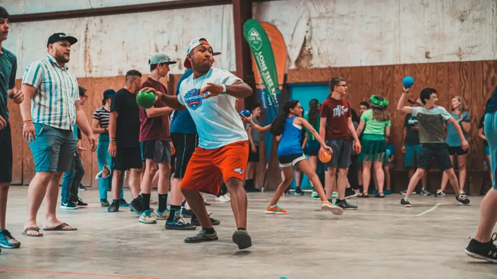 A large group of students and youth leaders playing a popular indoor youth ministry game, dodgeball. The image is used to emphasize how youth group games can help grow your ministry.