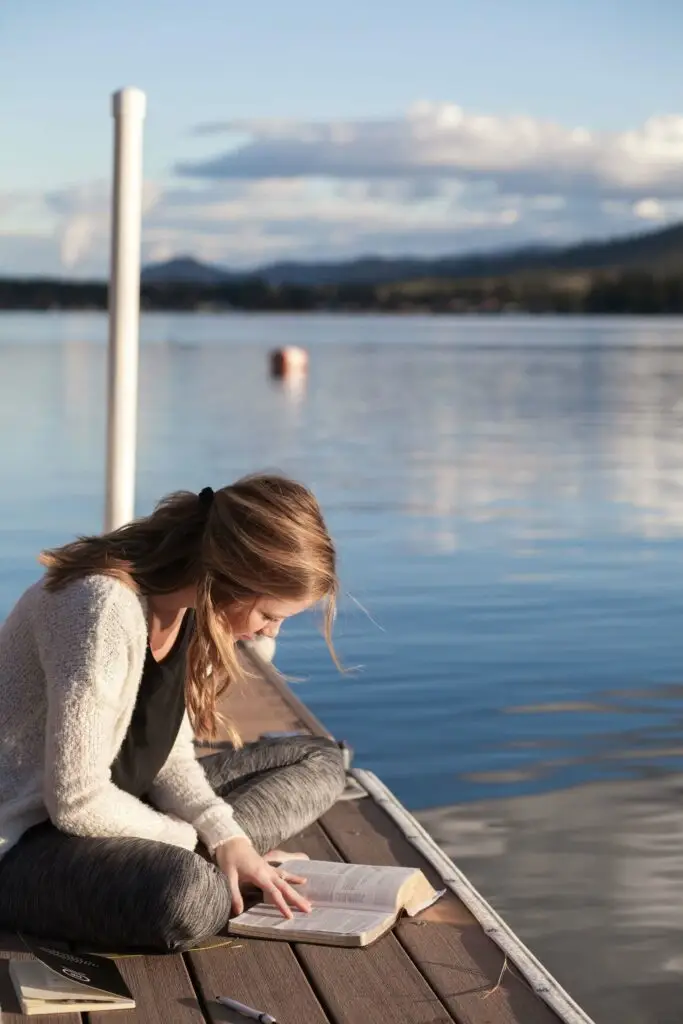 An image of a teen girl reading her bible on a dock representing Dare 2 Share's blog titled Youth Pastors: Here's Why You Should Focus on Spiritual Growth, Not Just Numbers.