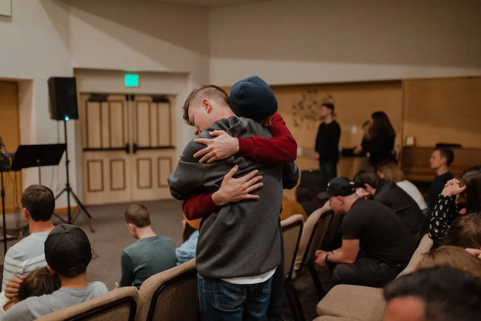 An image of 2 teen boys hugging in church representing Dare 2 Share's blog titled Youth Pastors: Here's Why You Should Focus on Spiritual Growth, Not Just Numbers